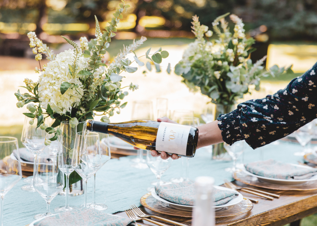 A woman skillfully pours wine into a glass, embodying the essence of a sophisticated gathering. - Private Chefs to Book Now