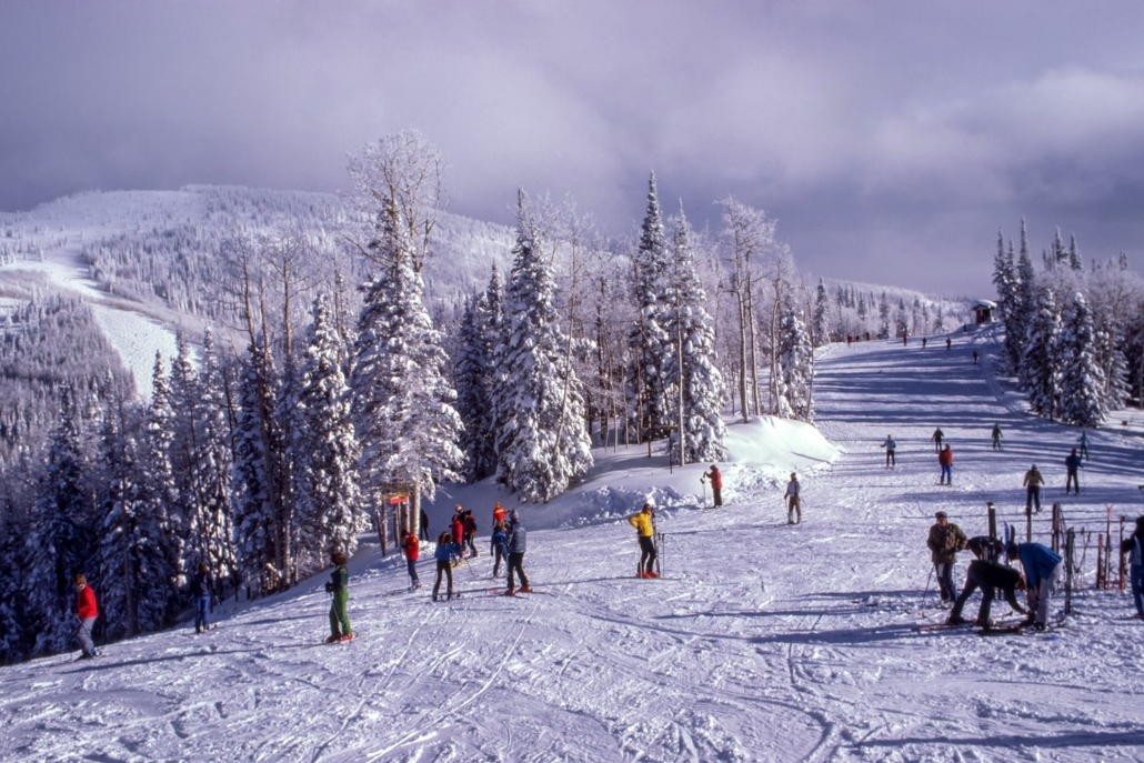A group of skiers enjoying the slopes at Buttermilk Ski Resort in Aspen, Colorado, surrounded by snowy mountains.