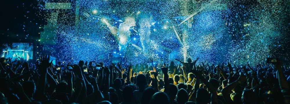 Concertgoers at an X Games event, with blue lighting effects and confetti creating a festive atmosphere.