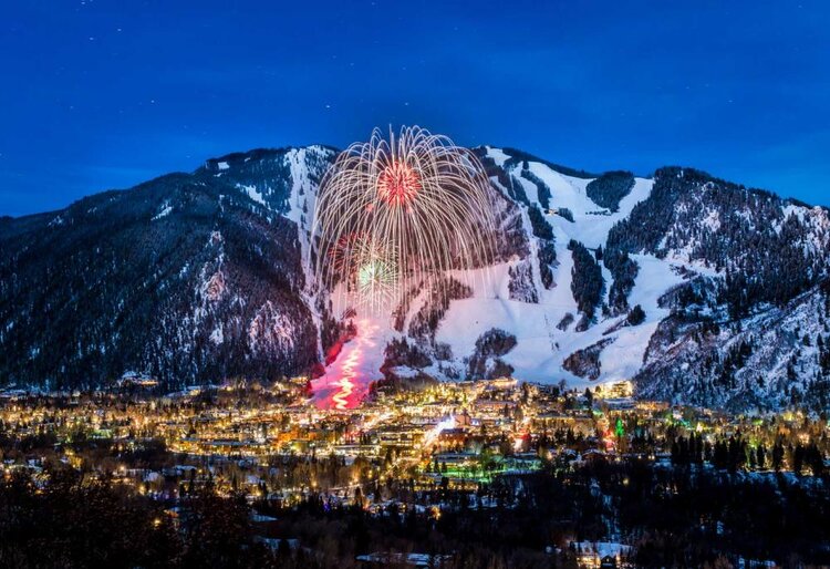 A dazzling display of fireworks lights up the skyline and mountains, marking a winter celebration in Aspen Mountain.