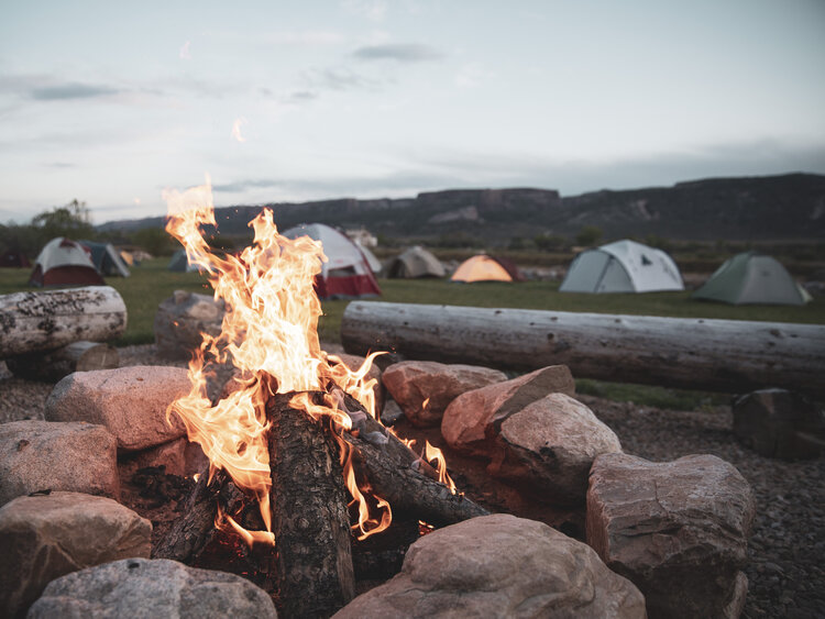 A warm campfire glows brightly in Aspen camping spot, creating a cozy outdoor atmosphere.