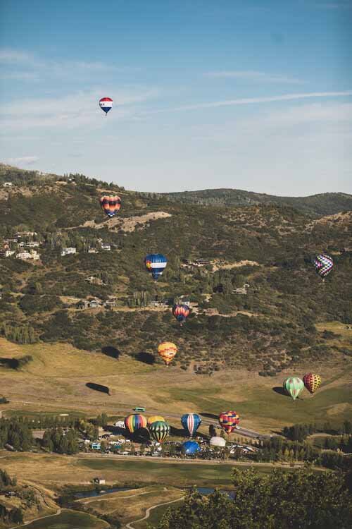 A vibrant scene of hot air balloons ascend above Aspen landscape, creating a stunning aerial display against the sky.