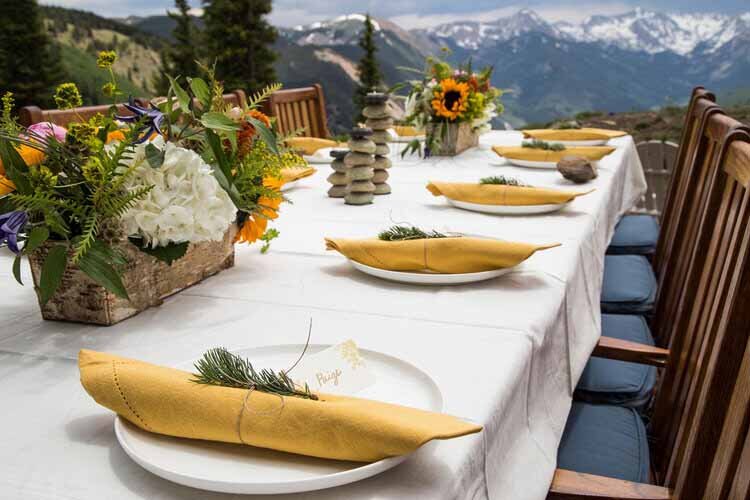 An exquisite dinner table set for an event, showcasing stunning mountain views in the background.