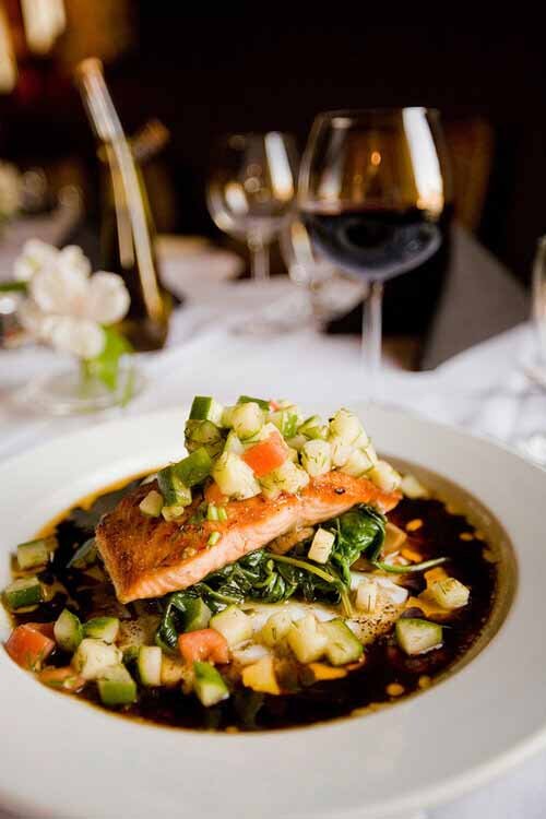 A gourmet plate featuring fish and fresh vegetables, elegantly presented on a table by Aspen Luxury Concierge.