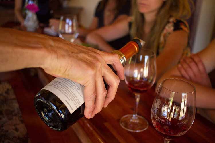 A person pours wine into a glass during an Aspen Luxury Concierge event, capturing the essence of luxury and enjoyment.