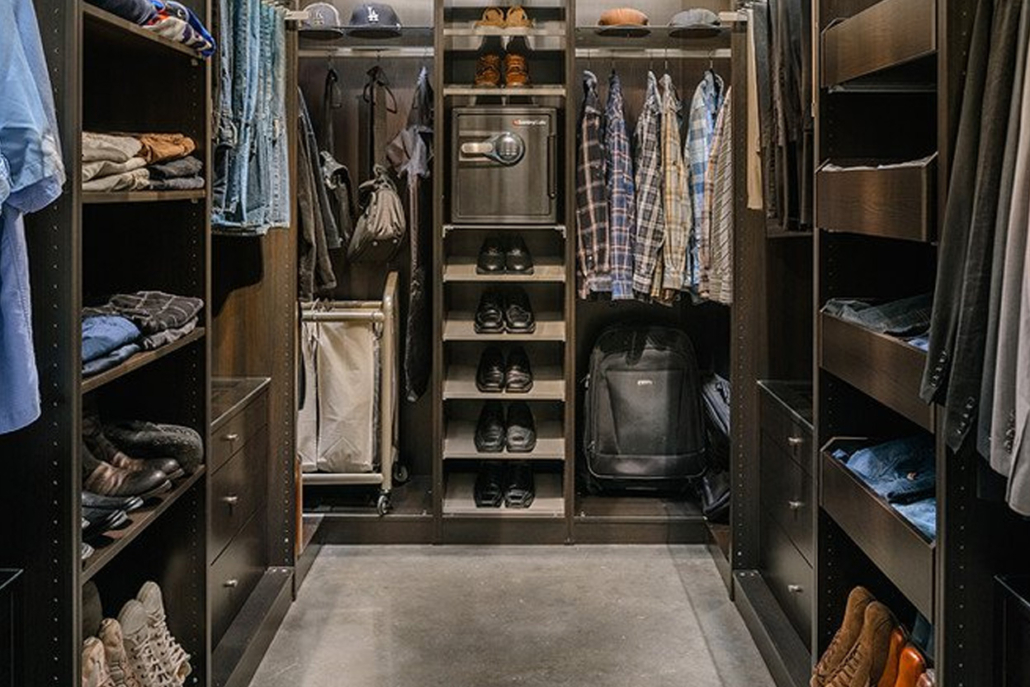 A well-organized walk-in closet with a large mirror reflecting various clothing items.