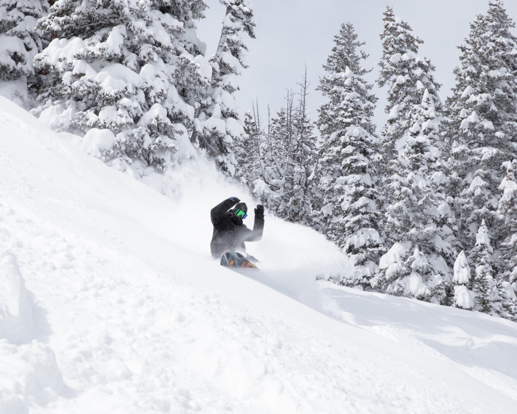 A person skillfully rides a snowboard down a pristine, snow-covered slope in winter with Aspen winter ski guide 2020-2021