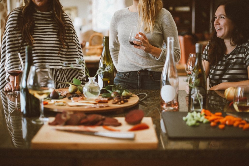 A group of people gather around a table filled with food and wine, enjoying a delightful meal together with 2020/2021 winter Aspen dining guide