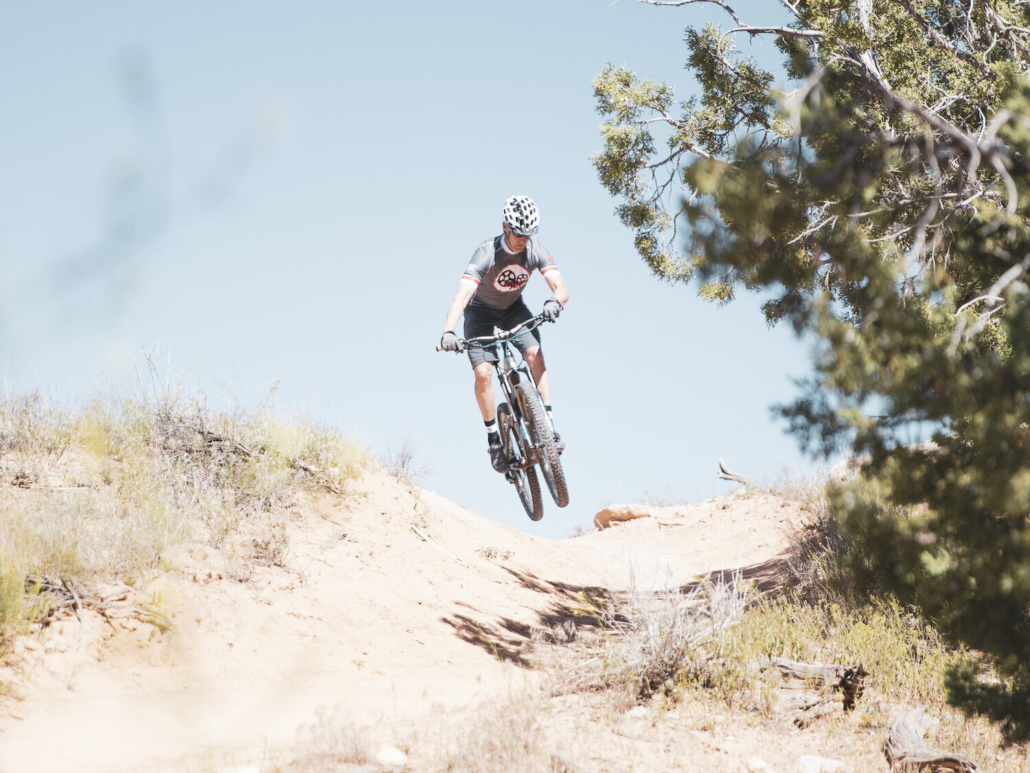 A person rides a mountain bike along a rugged dirt path, embracing one of the best things to do in Aspen in summer