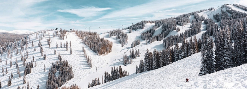 A person skillfully skis down a snowy slope at Aspen, enjoying the winter landscape.