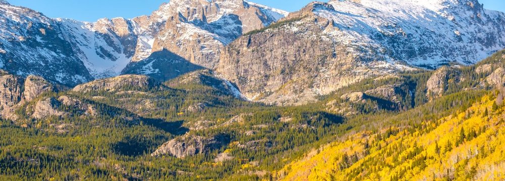 Snow-covered Rocky Mountains surrounded by lush trees, perfect for Aspen Hikes adventures.