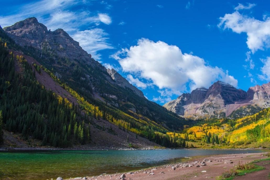 A picturesque view of the Maroon Bells, surrounded by lush greenery and a clear blue sky.