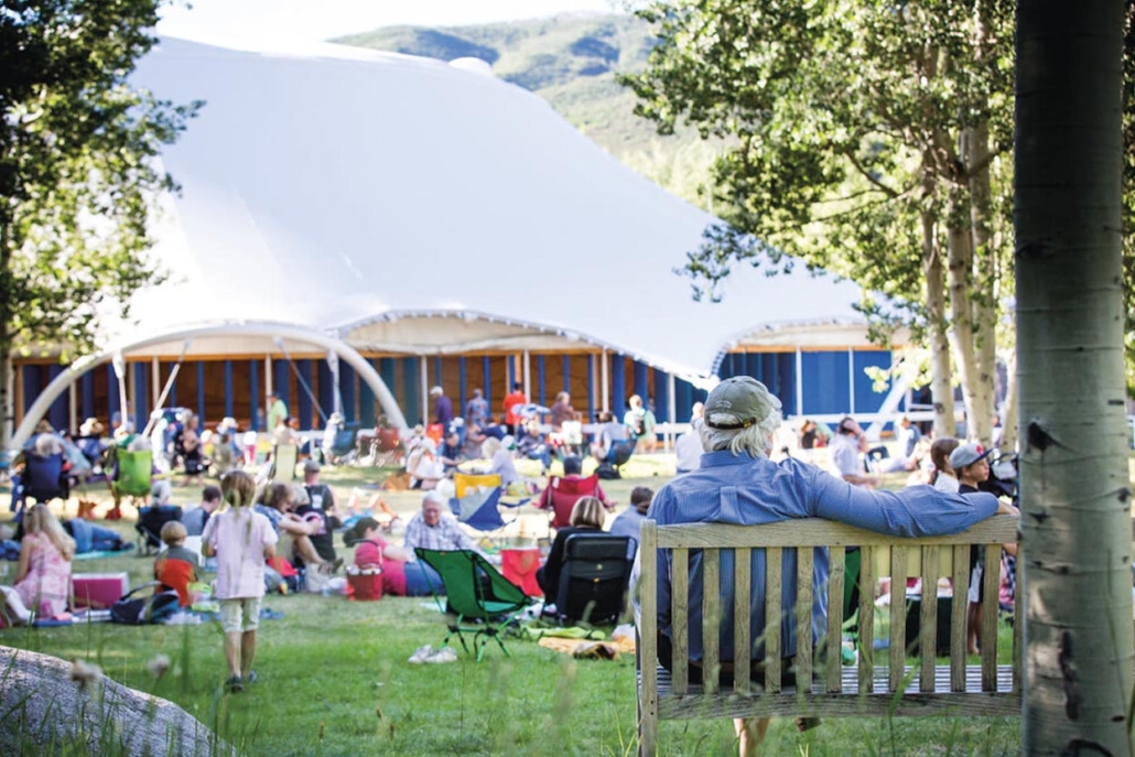 A man sits on a bench, relaxing and enjoying the outdoors during Aspen music festival