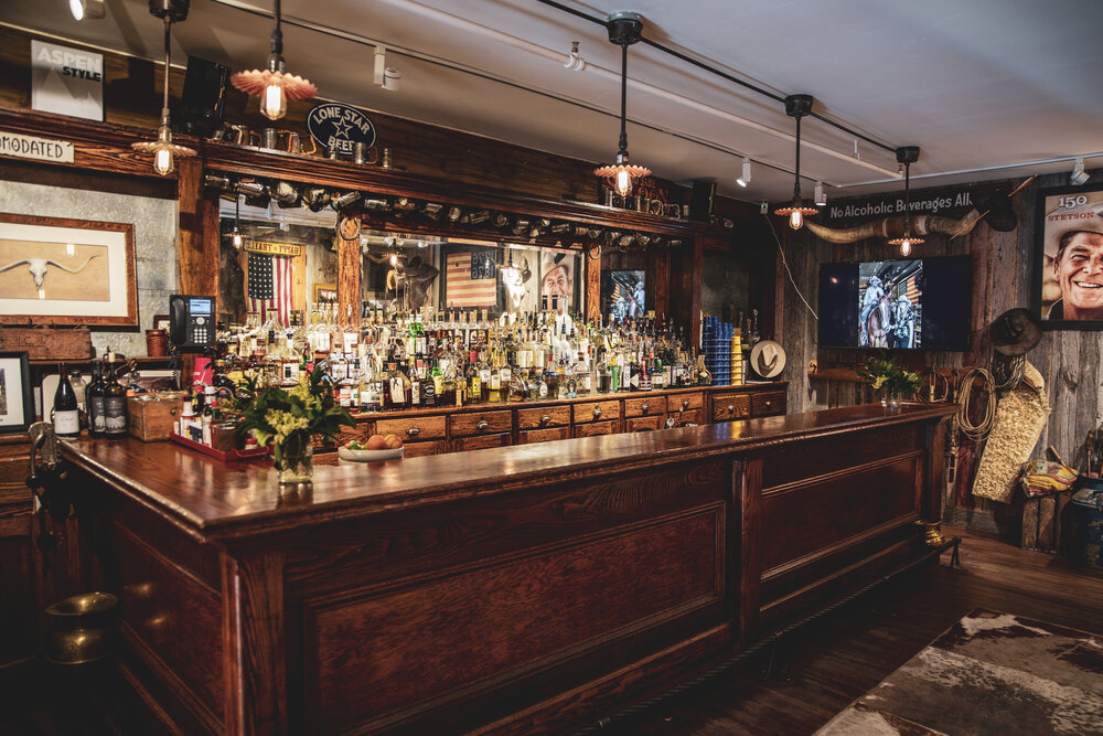 An inviting bar scene with a polished wooden counter and a chic cowhide rug beneath.