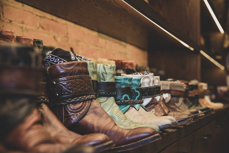 A shelf in a store featuring an assortment of boots, each pair showcasing unique styles and colors in Aspen private shopping experiences