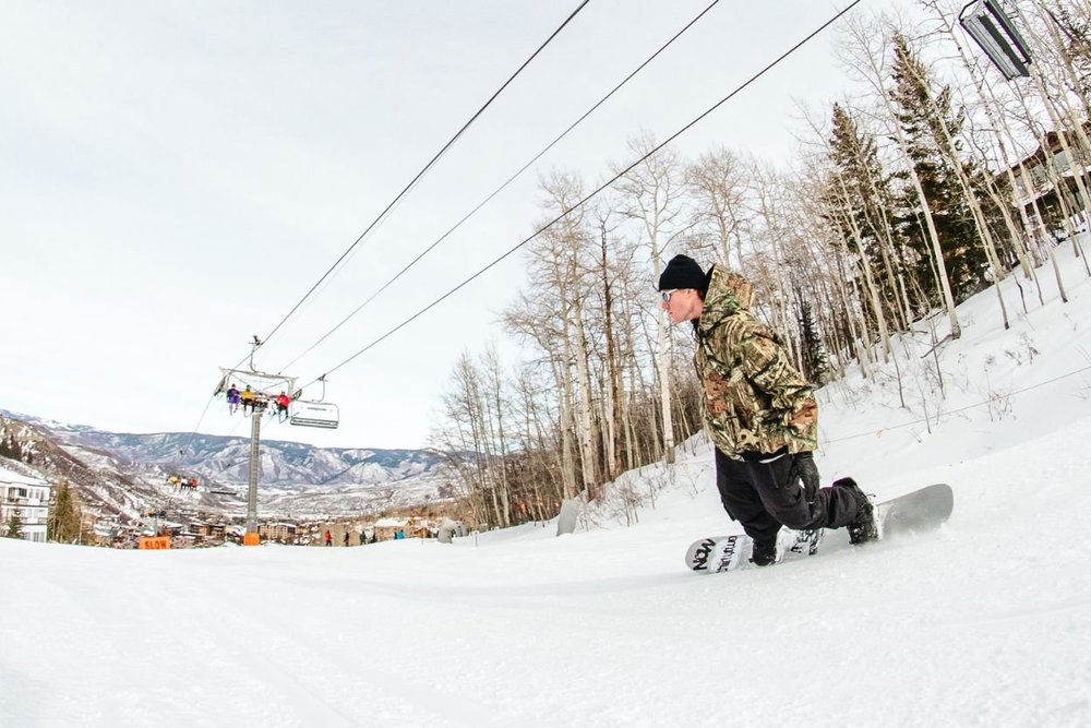 A young man snowboards down a slope, showcasing his skills in a winter wonderland.