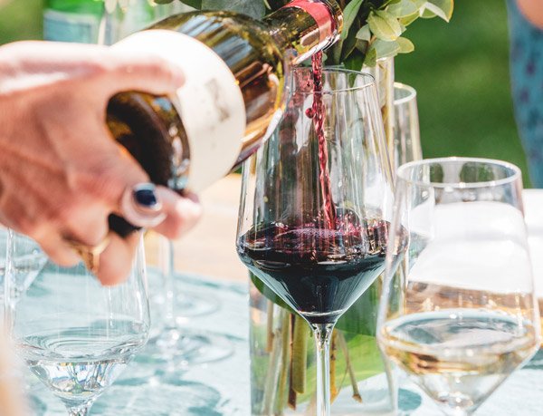 A person gentle pours red wine into a glass during Aspen food and wine festival.