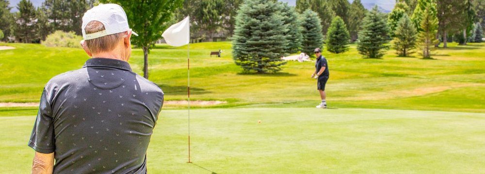 A golfer takes a shot on a vibrant green field, highlighting the charm of Golf Courses in Aspen.