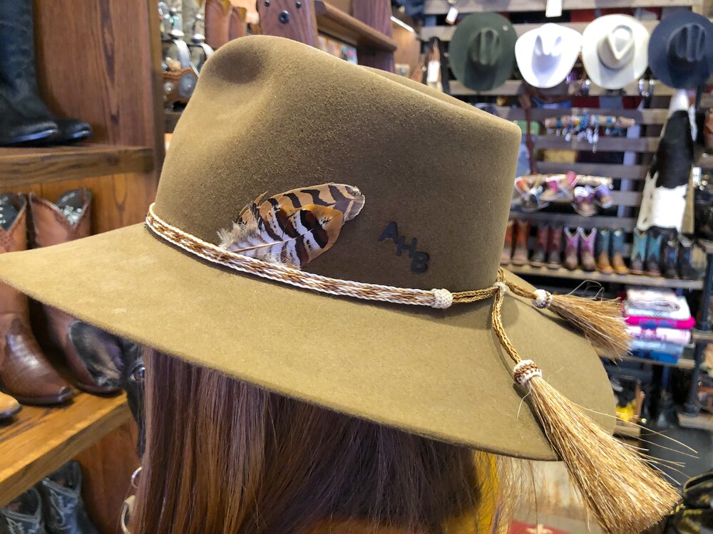 A fashionable woman wearing a feathered and tassel hat, showcasing her unique style and sophistication.