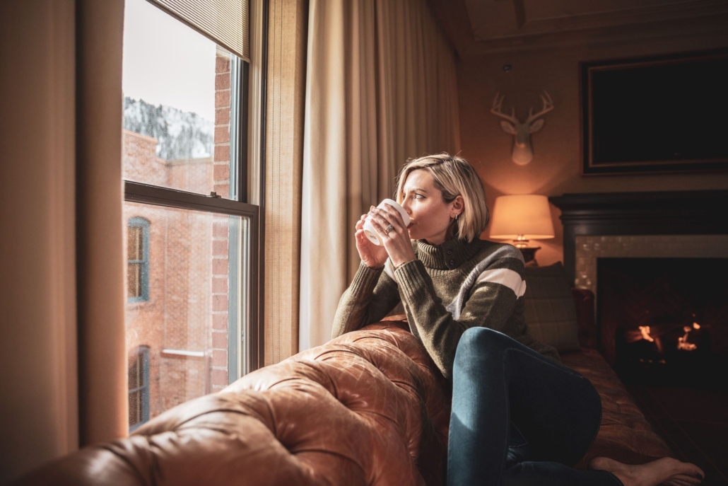 A woman sits comfortably on a couch, sipping coffee and enjoying a moment of tranquility.