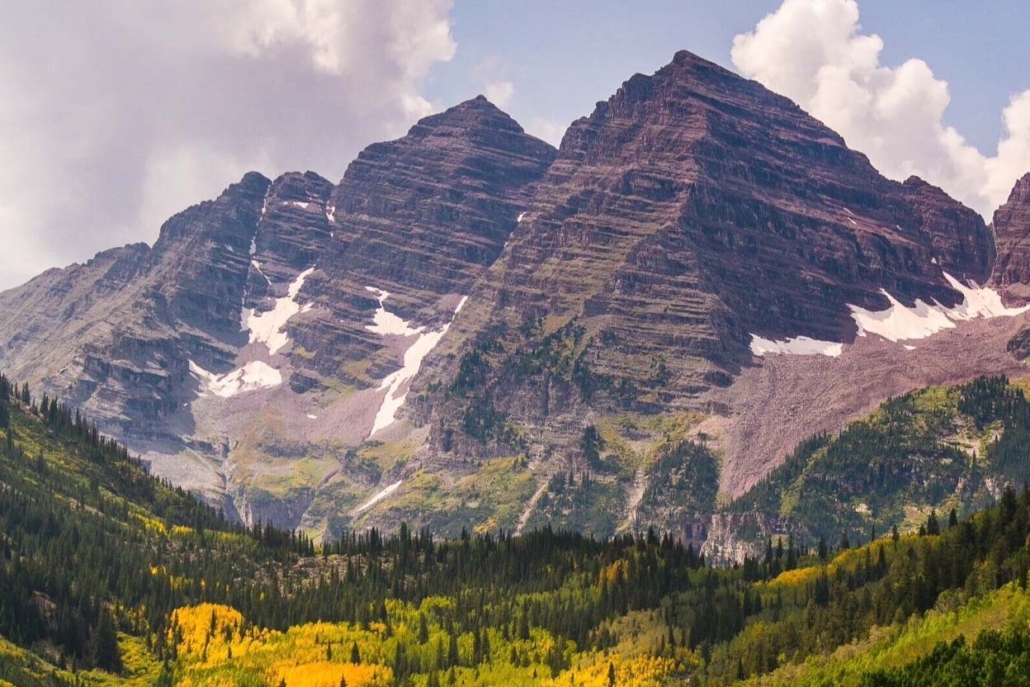 Scenic view of Maroon Bells with vibrant foliage and a clear blue sky enhancing the picturesque landscape.