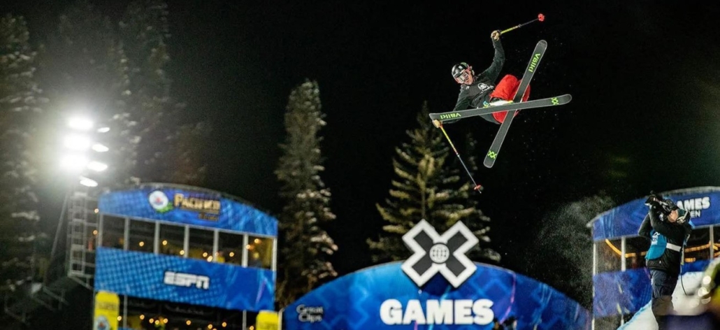 A skier performs a mid-air jump during nighttime, showcasing the excitement of Aspen sports