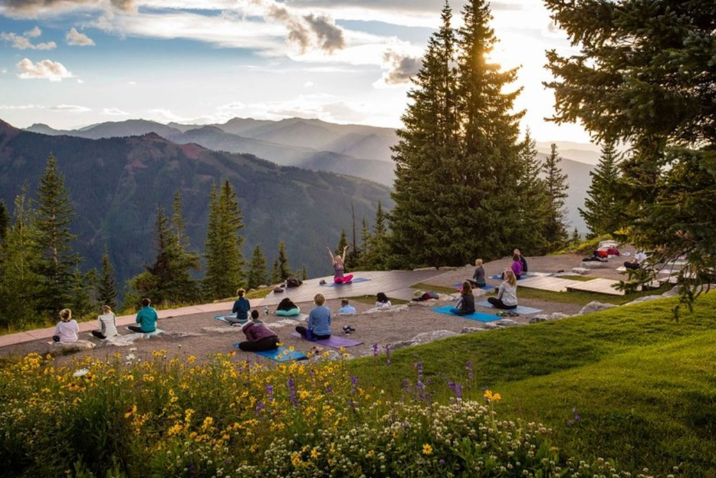 One of the best aspen summer activities is yoga with other people on a mountain peak, with stunning mountains visible in the distance.