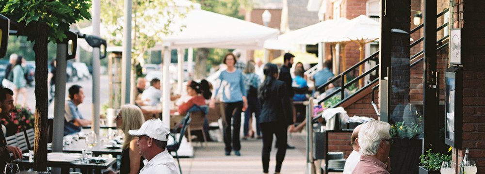 People seated at tables outside cafes, highlighting the outdoor lively dining scene.