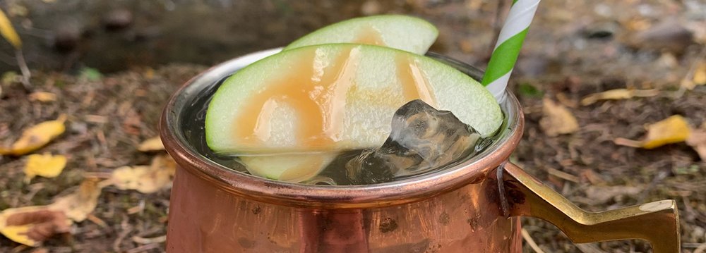 A copper mug filled with fresh fruit slices and a straw, perfect for occasions