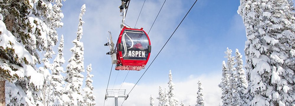 silver queen gondola travels upward through a snowy mountain scene, highlighting the beauty of Aspen in winter.