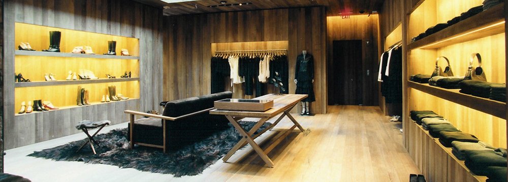 A cozy room featuring wooden shelves filled with fashion things and a sleek black chair for seating.