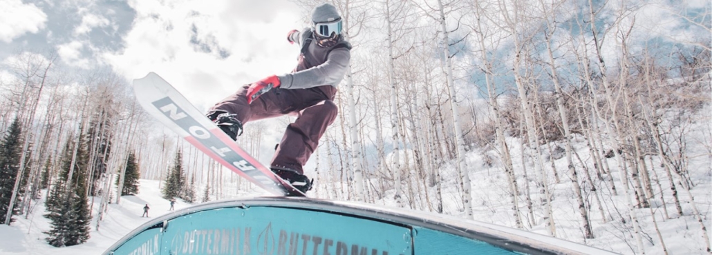 A snowboarder performs a trick on a ramp at Aspen Colorado Ski Resorts, showcasing skill and excitement.