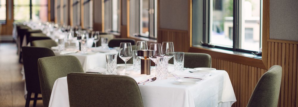 A beautifully arranged restaurant with tables and chairs set for an elegant dinner experience.