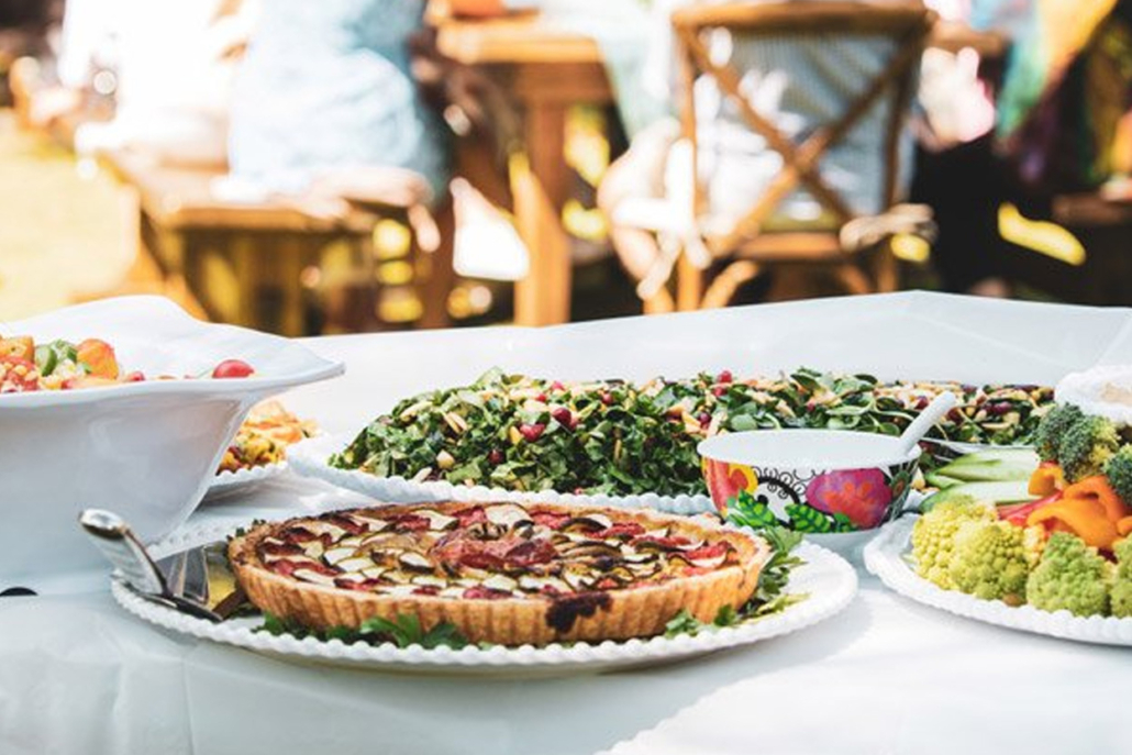 A table of various delicious dishes, surrounded by people enjoying a meal together.