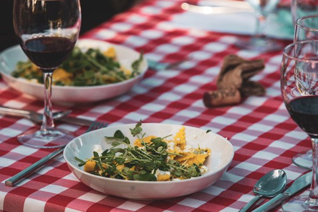 A table set with glasses of wine and a fresh salad, perfect for a dining experience.