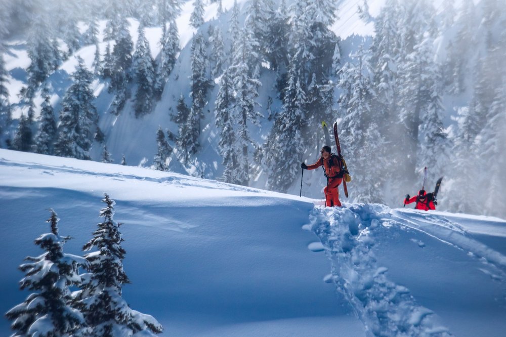 Two skiers navigate a snowy mountain at Highland Bowl Aspen, enjoying the winter landscape.