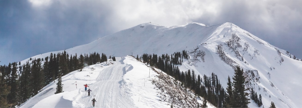 A skier gracefully descends a snowy mountain, enjoying the Highland Bowl Aspen Colorado vacation experience.