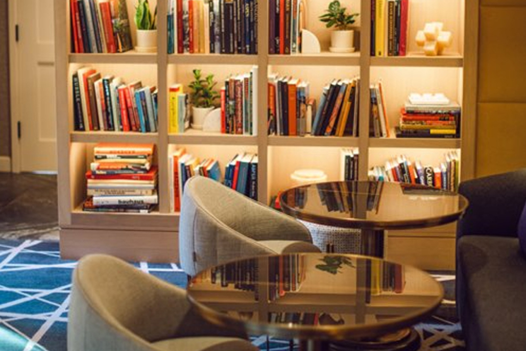 A cozy hotel lobby featuring bookshelves and comfortable chairs for guests to relax and read.