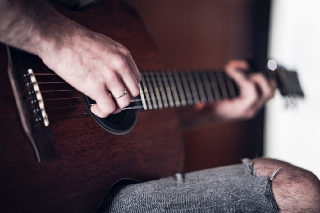 A musician engaged in playing an acoustic guitar, during Aspen songwriting retreat