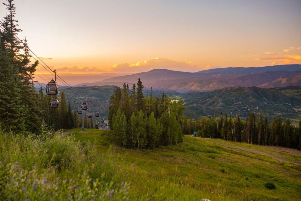 A picturesque sunset view of mountains with a ski lift silhouetted against the sky.