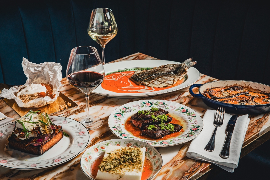 A dining table filled with an assortment of food and wine, representing the vibrant restaurant scene in Snowmass Village, Colorado.