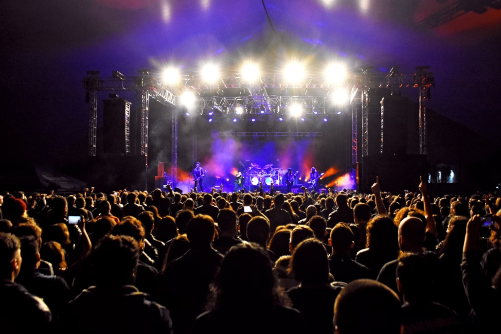 A lively audience at a concert in Snowmass Village, Colorado, with bright lights illuminating the night sky.