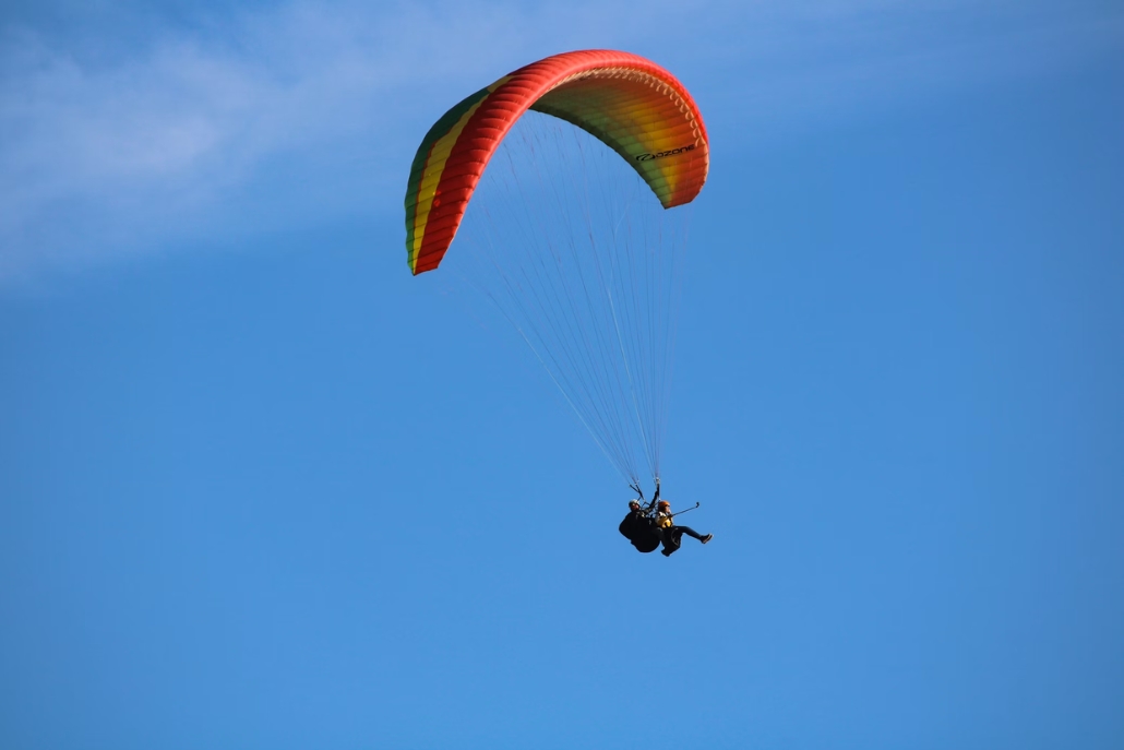 A tandem paraglider soaring through the blue sky, capturing the essence of a September paragliding tour in Aspen.