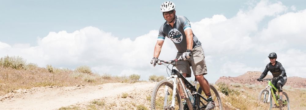 Two cyclists navigate a dirt path, enjoying the summer scenery of Aspen in July.