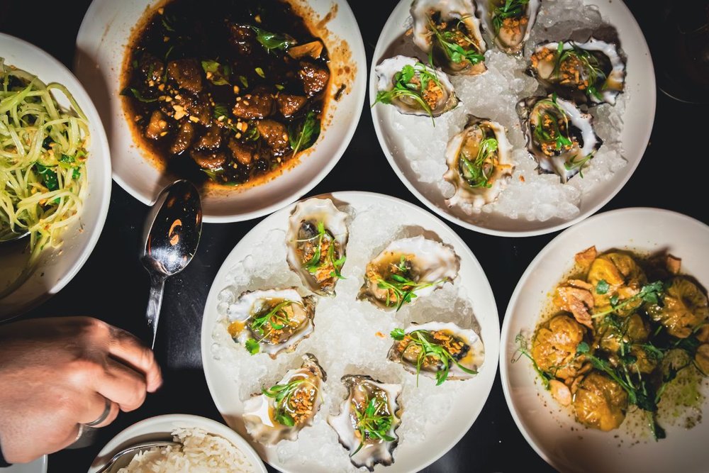 A table laden with various plates of gourmet food, showcasing a feast in Aspen