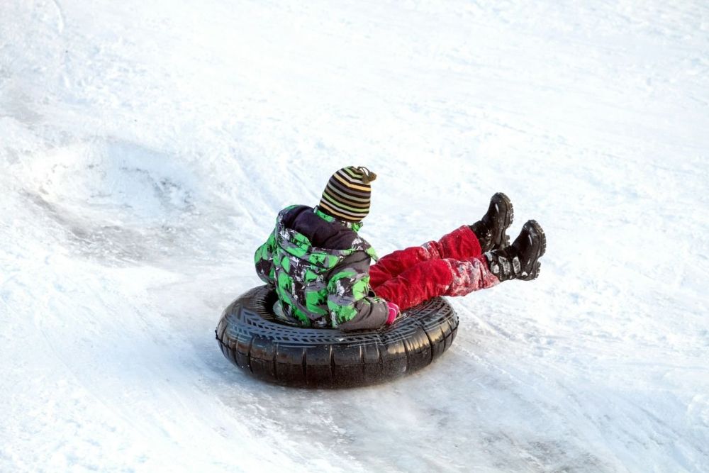 An individual slides down a snowy slope on a tube, enjoying a fun one of the things to do in Aspen in Winter