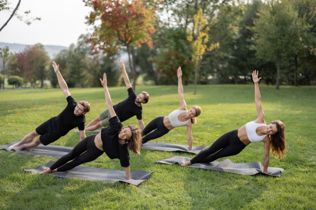 Individuals practicing yoga in a serene outdoor setting at Yoga Aspen, facilitated by ACES, with a clear blue sky above.