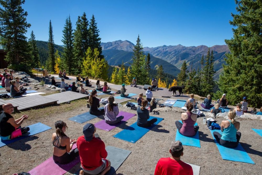 A group of people performing yoga poses in a breathtaking mountain landscape, showcasing harmony with nature and inner peace.