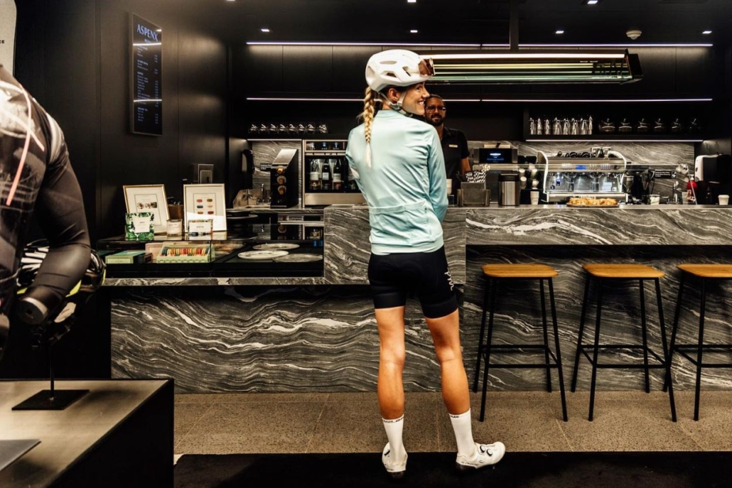 A cyclist stands in front of AspenX Café Aspen coffee shop, poised to take a break and savor a warm drink.