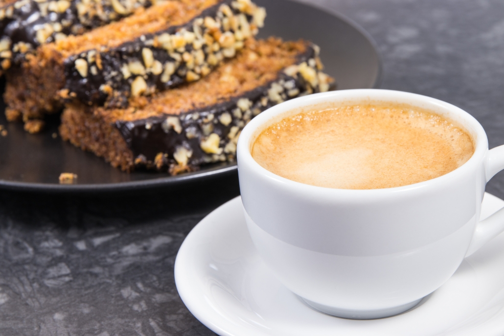 A cup of coffee and a slice of cake on a black table at Aspen Coffee Shops - Bakery & Café.